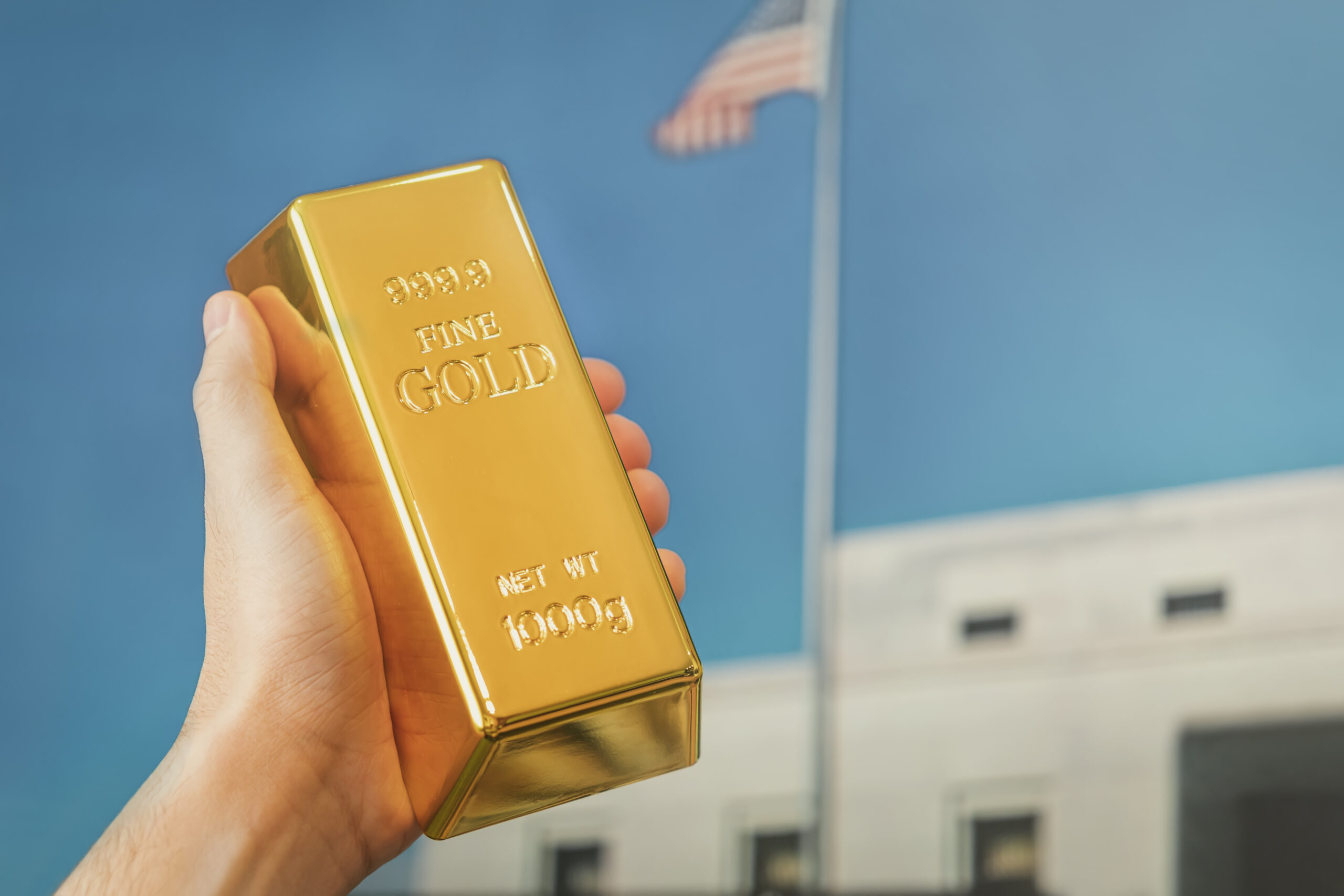 a gold bar in the hand of a man against the background of the gold vault of America.